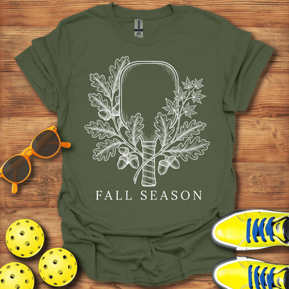 An olive green short-sleeve t-shirt with a white graphic of a hammer encased in oak leaves and acorns, with the text 'FALL SEASON' underneath. 