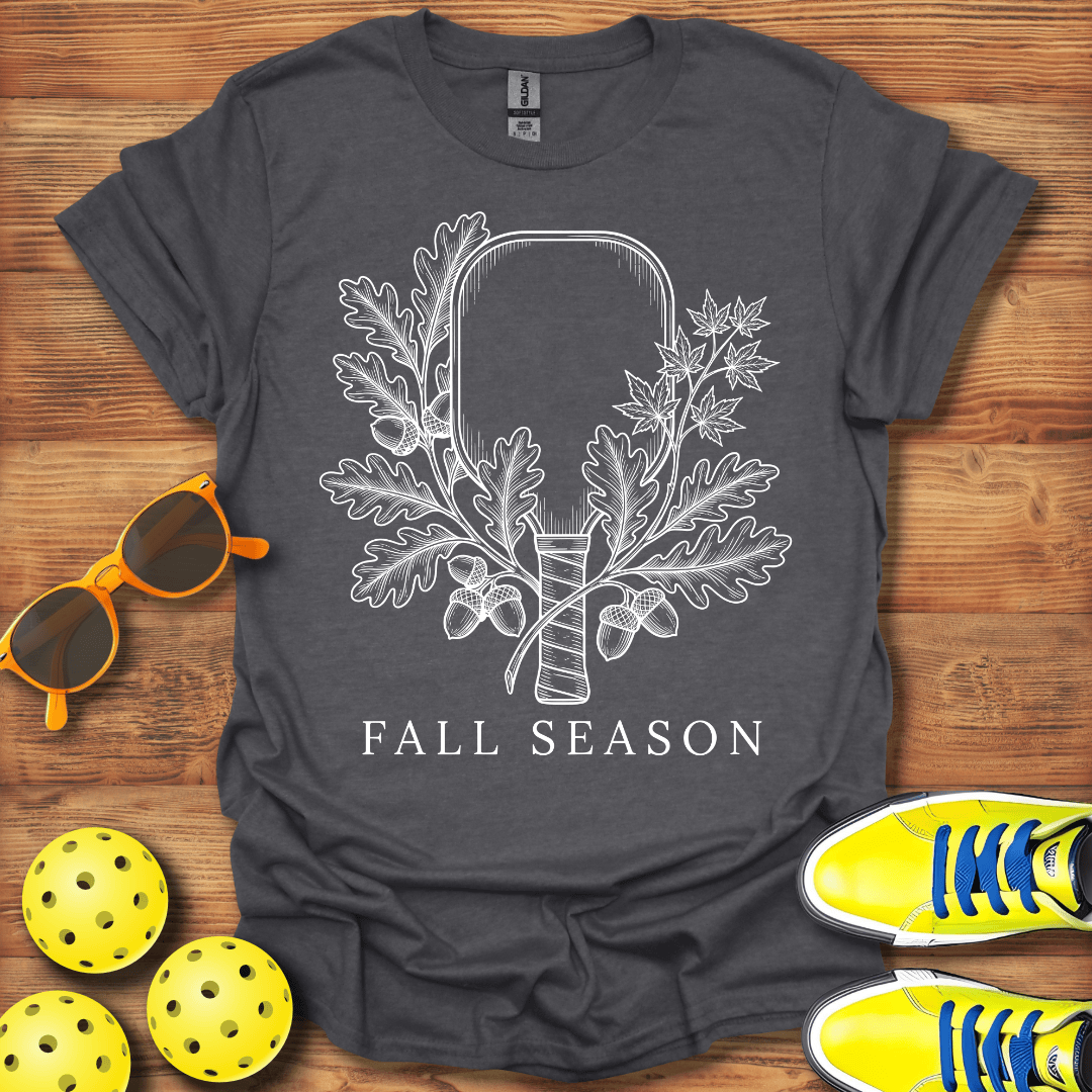 A dark gray graphic t-shirt featuring a white line art design of an axe surrounded by oak leaves and acorns, with the text 'FALL SEASON' underneath. 